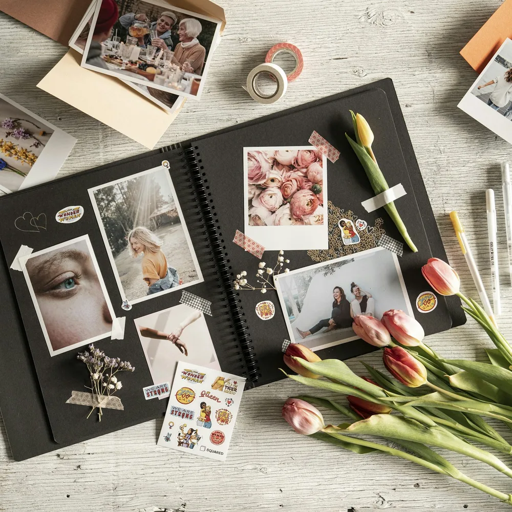 Álbum aberto com fotos, adesivos e flores