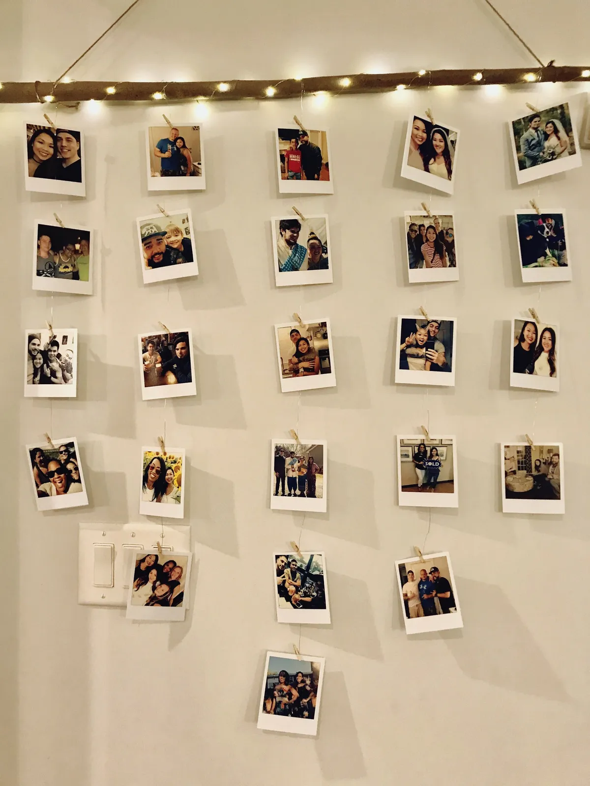Parede decorada com fotos Polaroid penduradas em varal com luzes